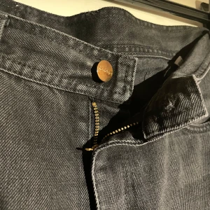 Svarta wide jeans från Rodebjer - Snygga svarta jeans från Rodebjer med breda ben och klassisk femficksdesign. Jeansen har hög midja, dragkedja och knapp framtill samt Rodebjer-logga på bakfickan. Perfekta för en chill och trendig look.