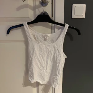 Vit croppad linnetopp från H&M - En enkel och fräsch vit croppad linnetopp från H&M. Toppen är ärmlös med rundad halsringning och tillverkad i mjuk bomull. Perfekt att matcha med jeans eller kjol för en clean och stilren look.