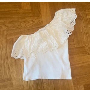 Vit offshoulder topp med volang - Superfin vit offshoulder topp med bred volang och broderade blommor längs kanten. Ny skick på toppen och nästan aldrig använd! ❣️❣️