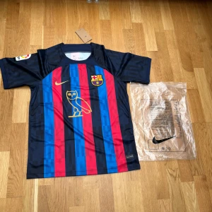 FC Barcelona Pedri matchtröja Nike - Snygg FC Barcelona matchtröja från Nike med Pedri och nummer 8 på ryggen. Tröjan har klassiska blå och röda ränder, guldiga detaljer och klubbmärke på bröstet. Tillverkad i lätt och ventilerande material, kortärmad och perfekt för fotbollsfans.