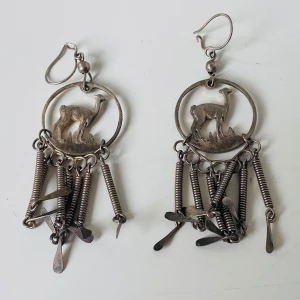 Unika silverörhängen med lama - Coola handgjorda örhängen i silverfärgad metall med  utstansad lama i cirkel och hängande spiraler och små plattor. De har en bohemisk vibe och är ca 7 cm långa. Perfekta för dig som vill sticka ut med ett annorlunda smycke med etnisk känsla.