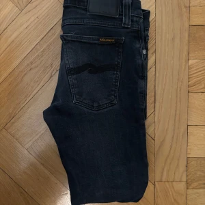 Mörkblå jeans från Nudie Jeans - Ett par fräscha mörkblåa nudie jeans utan defekter. Jeansen är i storlek 29/34 men passar närmare 28/32. Jeansen har varit använda fåtal gånger. Jeansen kommer med en sliten look helt nya och är perfekt för en grisch sommar!