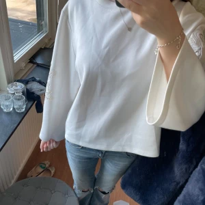 Vit tröja med broderade ärmar! - Vit tröja med vida långärmar och snygga broderade detaljer i vitt på båda ärmarna. Tröjan har en relaxed fit och är gjord i mjuk bomull, perfekt för dig som gillar en clean och stilren look med en twist. Jätte skönt material på insidan och jätte luftig. Knappt använd!💕