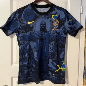 Blå Brasilien fotbollströja Nike M - Snygg blå Brasilien fotbollströja från Nike med unikt grafiskt mönster och gula detaljer. Tröjan har korta ärmar, svart krage och är tillverkad i lätt, tekniskt material med Dri-FIT. Perfekt för dig som gillar fotboll!