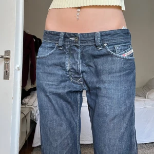 Diesel straight jeans låg midja blå - Säljer ett par jeans från Diesel med  raka ben. Herrmodell men passa både killar och tjejer. Jeansen har en snygg detalj med Diesel Industry-logga på myntfickan. Har lite slitningar bak, se sista bilden! Jag är ca 180cm, mått: Midja rakt över: 42 cm Midja runt om: ca 87 cm Innerbenslängd: 81 cm (kolla in min profil för fler jeans)