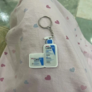 CeraVe nyckelring med lotionflaskor - Rolig nyckelring med två miniatyrer av CeraVe lotionflaskor i vitt och blått. Perfekt accessoar för dig som älskar hudvård och vill ha något unikt på dina nycklar eller väskan.