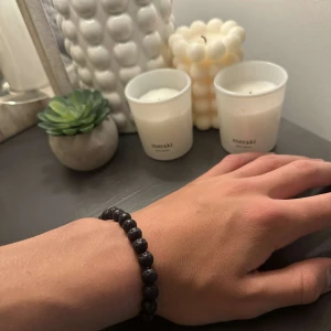 Svart armband med lavapärlor - Snyggt svart armband med runda lavapärlor som ger en cool och naturlig vibe. Elastiskt band gör det enkelt att ta på och av. Perfekt accessoar för dig som gillar minimalistisk och stilren design.