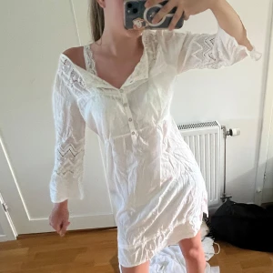 Vit spetsklänning med knappar - Supersöt vit kortklänning med spetsdetaljer och knappar framtill. Den är från Vila💕