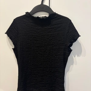 Svart ribbad topp från Kappahl - Svart ribbad topp från Kappahl i storlek XS. Toppen har korta ärmar och tightare passform💕