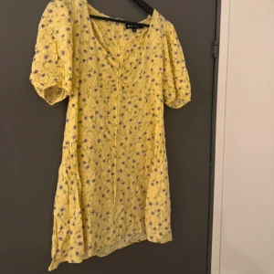  kortklänning från Motel - Bundle rabatt finns!❤️ gul kortklänning från Motel med lila blommor, puffiga korta ärmar och v-ringning med snörning framtill. Storleken kan anpassas lite efter bysten - storlk L men passar bäst på S-M