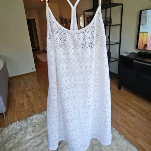 Vit spetsklänning från KappAhl - Superfin vit klänning från KappAhl med tunna axelband och spetsmönster. Lätt och luftig med snyggt fall, perfekt för varma dagar. Tillverkad i stretchig polyesterblandning som ger en bekväm passform. Snygg detalj med öppen rygg och smala band.