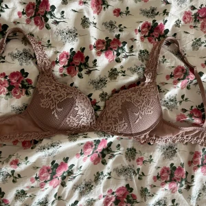 Rosa spets-bh från Intimissimi - Supersöt bh från Intimissimi i en ljusrosa nyans med vacker spets och blommigt mönster. Kuporna är vadderade och axelbanden har fina spetsdetaljer. Perfekt för dig som gillar romantiska och feminina underkläder. Storlek 75B säljs pga för liten.