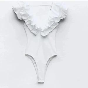 Zara body - Supersnygg vit body med djup v-ringning och stora volanger runt axlar och hals. Perfekt för allt Sitter tajt och har en klassisk, stilren look. Materialet känns mjukt och följsamt. Är i L men passar mig som bär S helt utan problem!🥰
