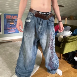 Baggy jeans  - Säljer ett par jeans från jaded med  broderat cyber mönster längs ena benet. Jeansen har slitna detaljer och passar alla midjemått, riktigt fräna 😽😽