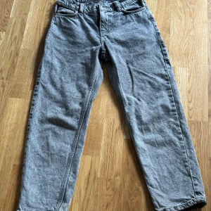 Grå loose fit jeans från Grunt - Snygga gråa jeans från Grunt i loose fit-modell. Byxorna har klassisk femficksdesign, bälteshällor och raka ben. Materialet är jeans i en askgrå tvätt som ger en cool, avslappnad vibe. Perfekta för dig som gillar en lite mer relaxed stil.