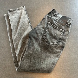 Replay Anbass  - Snygga Replay Anbass jeans i grå tvätt med coolt sliten look. Modellen är slim fit och tillverkad i stretchigt Hyperflex-material för extra komfort. Klassisk femficksdesign och normal midja. Perfekta för dig som gillar en modern och stilren vibe. Priset kan diskuteras 