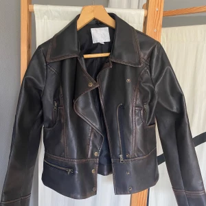 Brun skinnjacka från Amisu, stl 36 - Snygg brun skinnjacka från Amisu i klassisk bikerstil. Lite kortare i längden. Typ aldrig använd!