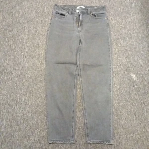 Gråa high waist jeans från H&M - Säljer ett par gråa högmidjade jeans från H&M i storlek 38. Jeansen har raka ben, klassiska femficksdetaljer och är tillverkade i denim. Perfekta för en chill och stilren look.