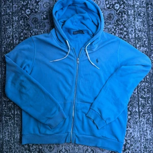 Blå hoodie från Polo Ralph Lauren - Snygg blå hoodie, Ralph Lauren. Köpts från zalando för ca ett år sedan, använd väldigt lite. Storlek L. väldigt bra skick, inga defekter alls! Hör av dig vid frågor eller prisförslag 