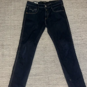 Replay Anbass mörkblå jeans - Snygga Replay Anbass jeans i mörkblå tvätt med klassiska kontrastsömmar och femficksdesign. Jeansen har en slim passform och är tillverkade i stretchigt jeanstyg för extra komfort. Perfekta för dig som gillar stilrena och moderna jeans.