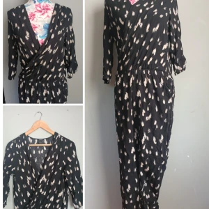 Svart omlott jumpsuit från Lindex stl S - Svart jimpsuit  från Lindex med vitt abstrakt mönster. omlottliv, resår i midjan och trekvartsärm. Luftigt material som känns skönt mot huden och ger en avslappnad men ändå snygg look. Fint skick och inget att anmärka på..
