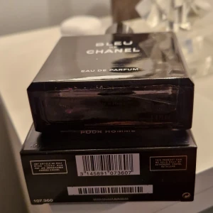 Bleu de Chanel Eau de Parfum 100ml - Bleu de Chanel Eau de Parfum för herr, 100ml. Flaskan är stilren och fyrkantig i mörkblått glas med svart lock och tydlig Chanel-logga på toppen. Kommer med originalkartong i matchande mörkblå färg och vit text. En ikonisk och elegant doft. 