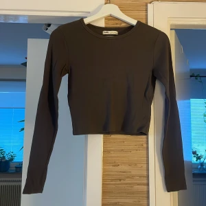 Grå ribbad croppad tröja Pull&Bear - Säljer en grå ribbad långärmad tröja från Pull&Bear i croppad modell. Tröjan har rund halsringning och är i ett stretchigt material som sitter snyggt på kroppen. Perfekt att styla med höga jeans eller kjol.