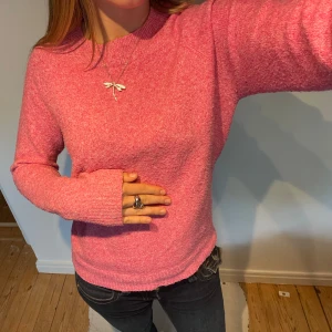 Rosa stickad tröja från Vero Moda - Mysig rosa stickad tröja från Vero Moda med rund halsringning och långa ärmar. Perfekt för att hålla sig varm och snygg under kyliga dagar. Enkel och stilren design som är lätt att matcha med jeans eller kjol.