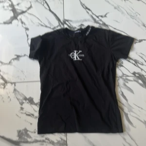 Svart Calvin Klein t-shirt med brodyr - Svart t-shirt från Calvin Klein Jeans med klassisk broderad CK-logga i vitt på bröstet. T-shirten har rund hals, korta ärmar och är gjord i mjuk bomull. Perfekt för en clean och stilren look.