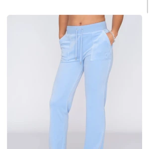 Mjukisbyxor i velour, blå & beige - Säljer två par mjukisbyxor i mjuk velour från juicy couture , ett par i ljusblått och ett i beige. Byxorna har bred resår i midjan med snörning, raka ben och stora fickor fram och bak med knappdetaljer. Säljer även koftan som är till dom beiga byxorna. Skicka pm för pris 