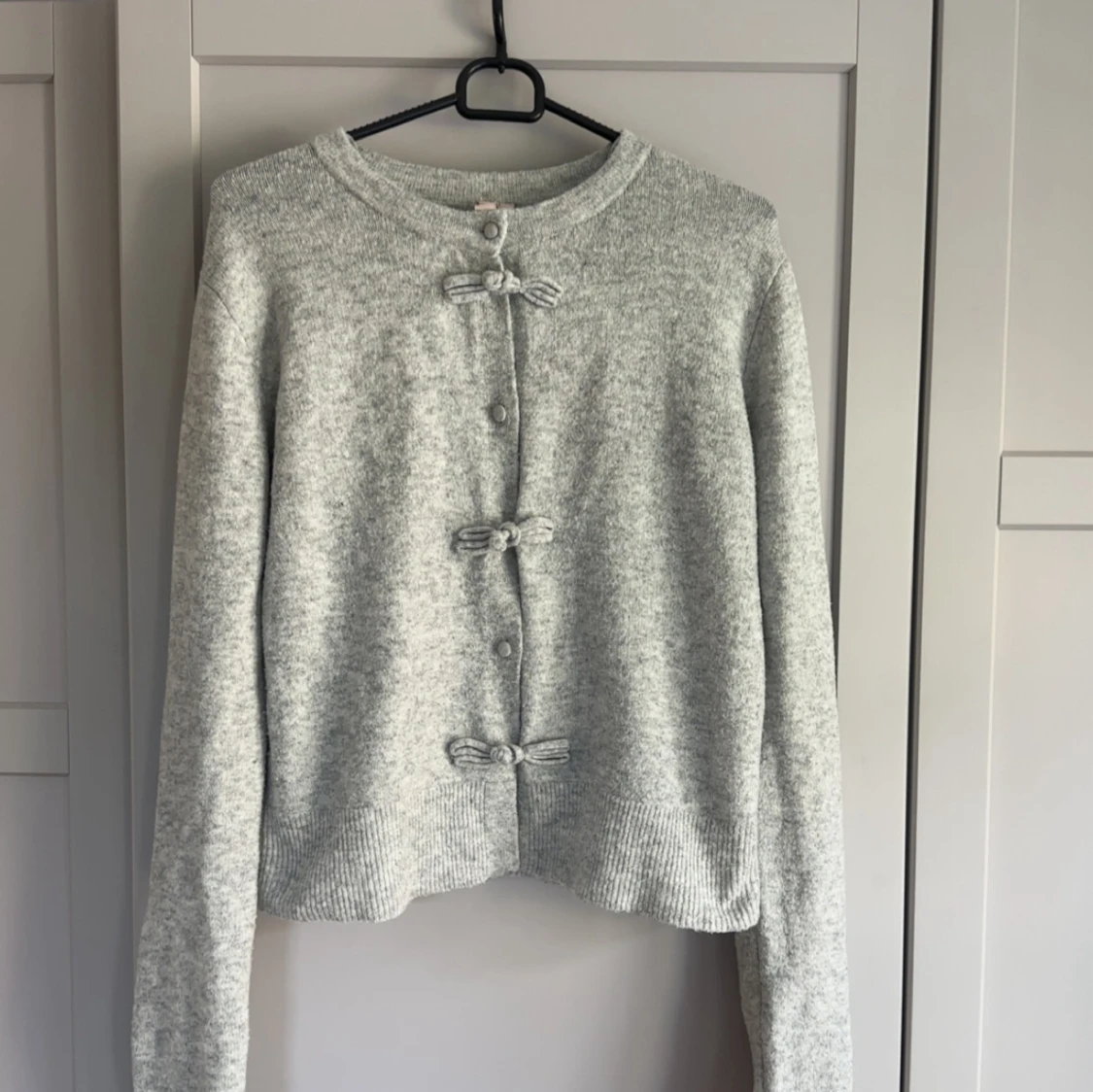 Ljusgrå kofta med rosettdetaljer