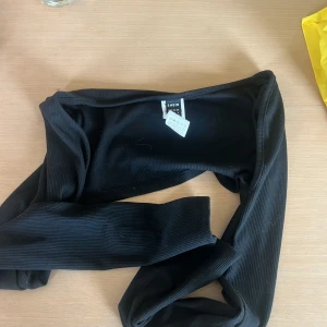 Svart ribbad bolero SHEIN - Trendig svart bolero från SHEIN. Boleron har långa ärmar och en croppad passform som ger en snygg siluett. Perfekt för dig som gillar stilrena och enkla plagg med en twist.