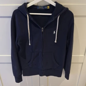 Marinblå zip up från Polo Ralph Lauren - Marinblå hoodie från Polo Ralph Lauren i XS. På bild 3 syns det att det finns några fläckar/noppor på framsidan, men annars i bra skick. 