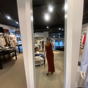 Brun långklänning med strukturerad yta - Säljer en snygg brun långklänning med strukturerad, lite krinklad yta. Klänningen är ärmlös med breda axelband och har en figurnära passform som framhäver siluetten. Perfekt för sommarens alla tillfällen!