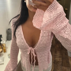 Ljusrosa spetsig blus med knyt - Supersöt ljusrosa blus i spets med v-ringning och knyt framtill. 