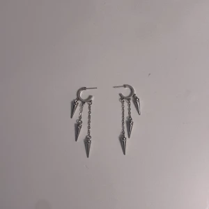 Silvriga örhängen med spikes - Coola silvriga örhängen med små ringar och hängande kedjor med spetsiga spikes. Ger en edgy vibe och passar perfekt för dig som gillar statement-smycken. Säljs som ett par. Inte äkta silver
