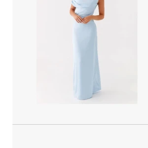 Ljusblå långklänning från Peppermayo - Säljer en elegant ljusblå långklänning i satin från Peppermayo. Klänningen har en axelbandslös design med draperad överdel och figurnära passform. Perfekt för bal eller festliga tillfällen. Materialet är glansigt och ger en lyxig känsla. Är upplagd nertill då den var för lång. Användaren är 161 cm lång och har klackar med ca 4-5 cm höjd.