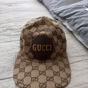 Gucci keps - Säljer en beige keps från Gucci med klassiskt GG-monogram. Justerbar baktill och är i väldigt bra skick.