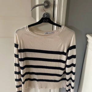 Randig långärmad tröja från Zara - Snygg långärmad tröja från Zara i beige med svarta horisontella ränder. Tröjan är tunnstickad och har en klassisk rund halsringning.