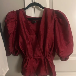Röd omlottblus med puffärm Gina Tricot - Supersnygg röd omlottblus från Gina Tricot med markerad midja och stora puffärmar. Blusen har v-ringning och lätt glansigt tyg som ger en lyxig känsla. Perfekt för dig som vill sticka ut med en trendig och färgstark topp.    Pris är diskuterbart!💞💞