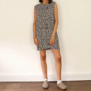 Svartvit kortklänning Bimba Y Lola - Kortärmad svart klänning från Bimba Y Lola med vitt abstrakt mönster. Modellen är rak och kort, med dragkedja i ryggen. Perfekt för dig som gillar en cool och modern look. Materialet känns lätt och smidigt mot huden.litet hål under armen. Knappt syns.