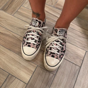 Converse All Star rosa leopard sneakers - Säljer ett par Converse All Star sneakers i storlek 39.5 med rosa och svarta leopardmönster. Skorna har vita snören, platt sula och klassisk rund tå. Ovandelen är i textil och sulan i gummi. Perfekt för dig som vill sticka ut med coola detaljer. Använder knappt längre.