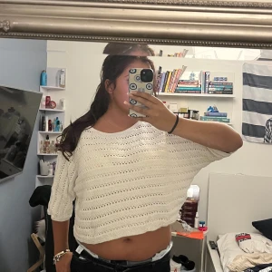 Vit croppad stickad tröja - Säljer en vit croppad stickad tröja med trekvartsärm. Tröjan har ett luftigt hålmönster och är perfekt för varmare dagar. Den har en avslappnad passform och rund halsringning. Superfin att styla med höga jeans eller kjol!