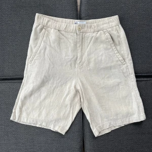 Linneshorts från Zara - Snygga beige shorts från Zara i luftig linnemix. Klassisk modell med normal passform, sidfickor och knäppning fram. Perfekta för varma dagar och ger en clean och stilren vibe. Passar dig som gillar enkel och tidlös stil.