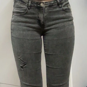 Grå bootcut jeans - Snygga grå bootcut jeans med slitna detaljer på låret. Perfekta för en avslappnad stil med en touch av edge. De har en klassisk design med en modern twist.
