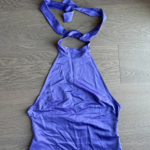 Lila halterneck-topp - Snygg lila halterneck-topp med knytband runt halsen från Asos. Perfekt för sommarens varma dagar. Toppens enkla design gör den lätt att matcha med olika outfits. 