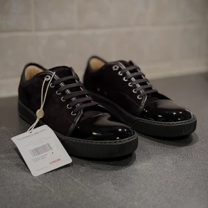 Lanvin Cap Toe - Helsvarta Lanvin Cap Toe i storlek UK 8 vilket motsvarar storlek 42/43. Skorna är i exemplariskt skick, det finns inga skador eller defekter och har blivit auktoriserade av Vestiaire Collection. Kvitto från Vestiaire finns.
