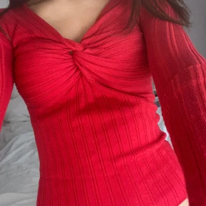 Röd ribbad topp - Snygg röd ribbad topp med lång ärm och knutdetalj framtill. Perfekt för att ge en färgklick till din outfit. Passar bra till både jeans och kjol.