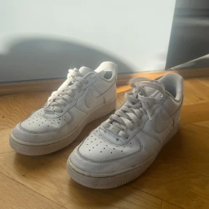 Vita Nike Air Force sneakers - Säljer ett par klassiska vita Nike Air Force sneakers. I använt skick med slitningar på vissa ställen. Se bilder för mer info. 