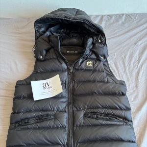 Svart dunväst från Bvaldi - Snygg svart dunväst från Bvaldi som jag köpte ny för 1 799kr och säljer nu för 1300kr.Använd fåtals gånger Jag är 181cm och den sitter bra på mig. Hör av dig för mer information!